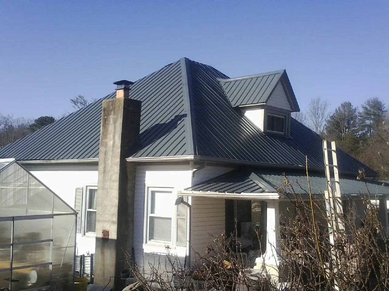 Dark blue standing seam metal roof on a white farmhouse with dormer — Slate & Tile Roof Repair by Roofing Brothers in Eastanollee
