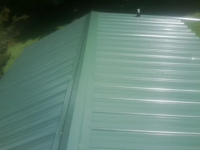 New green metal panels meeting at the ridge of a roof — Flat Roof Repair work by our crew in Eastanollee