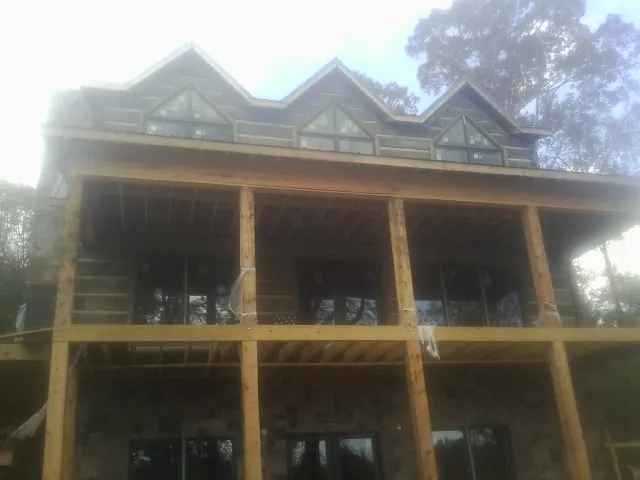 Dormers and porch framing on a large log home under construction — Roof Coating work by our crew in Eastanollee