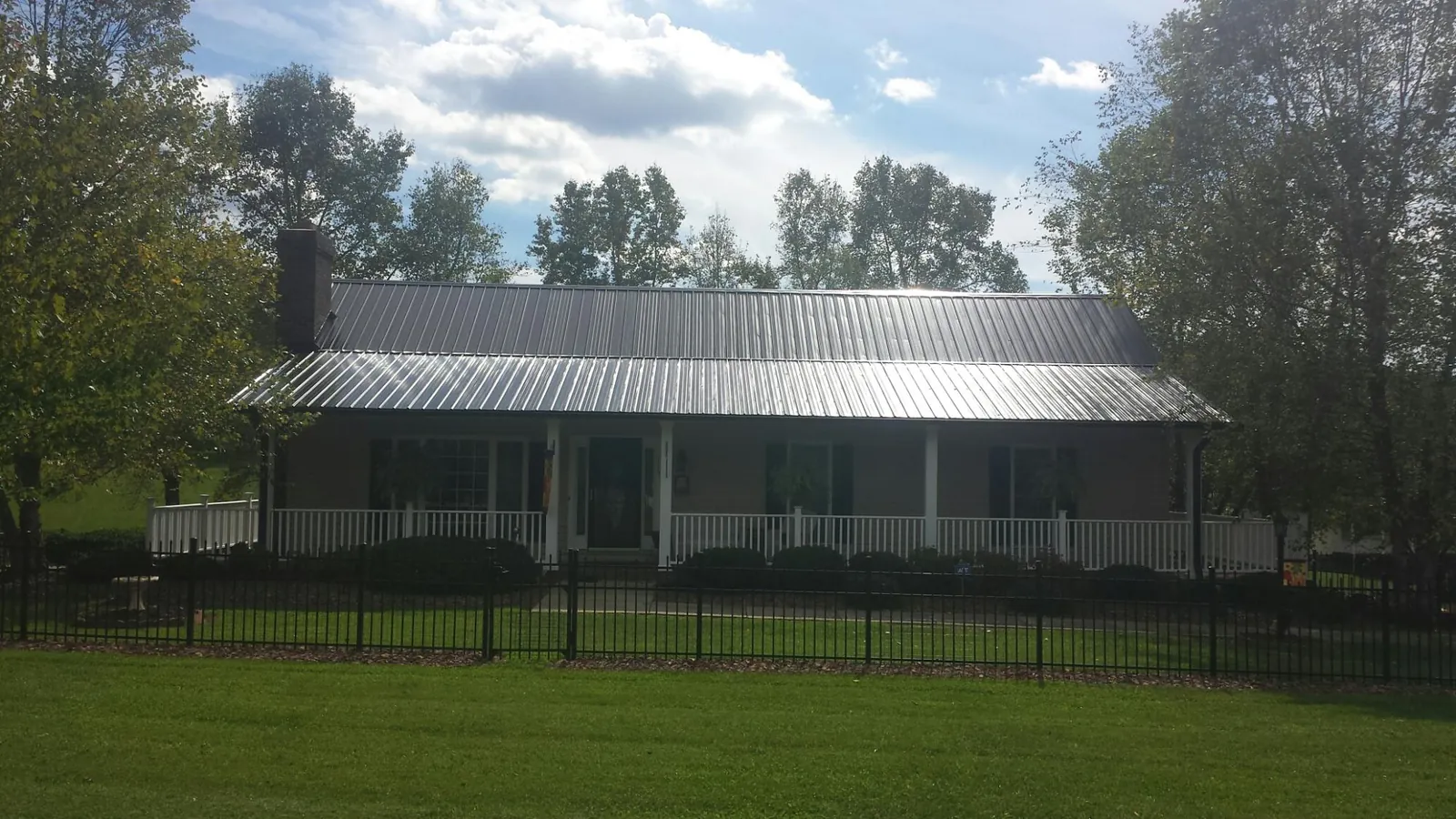 Gray metal roof on a brick ranch with a full width front porch — Gutter Guard Installation work by our crew in Eastanollee