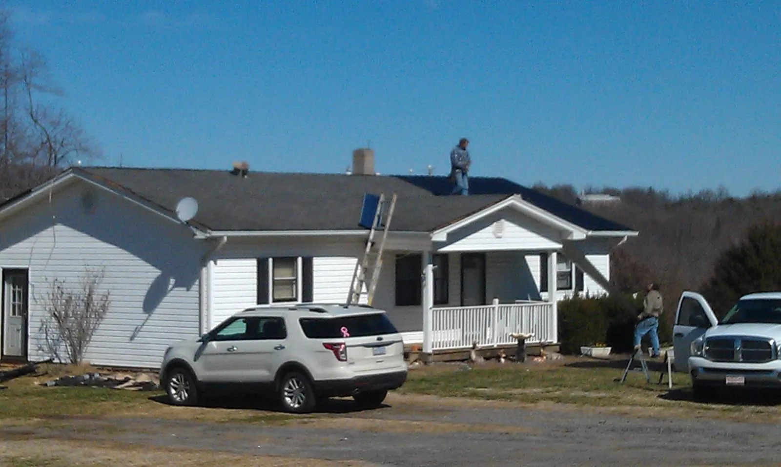 Roofers stripping shingles from a white ranch house roof in Eastanollee
