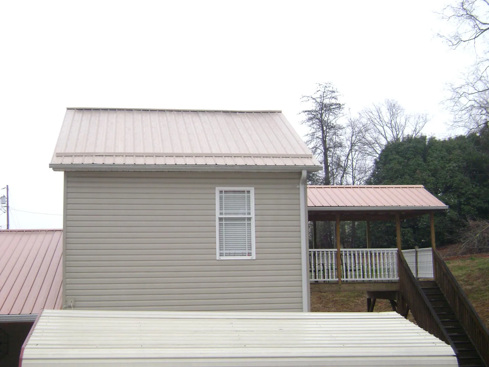 Tan metal roofs on a two story addition and attached porch, from a Roof Replacement job in Eastanollee