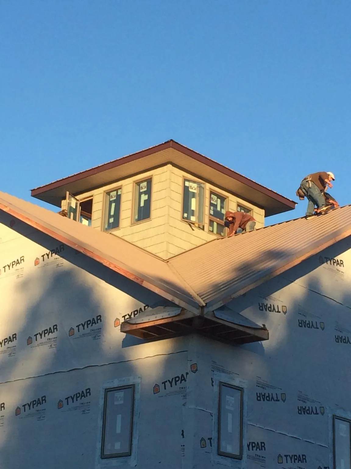 Roofers working around a rooftop cupola on a new metal roof at sunset — Roof Waterproofing in Eastanollee by Roofing Brothers